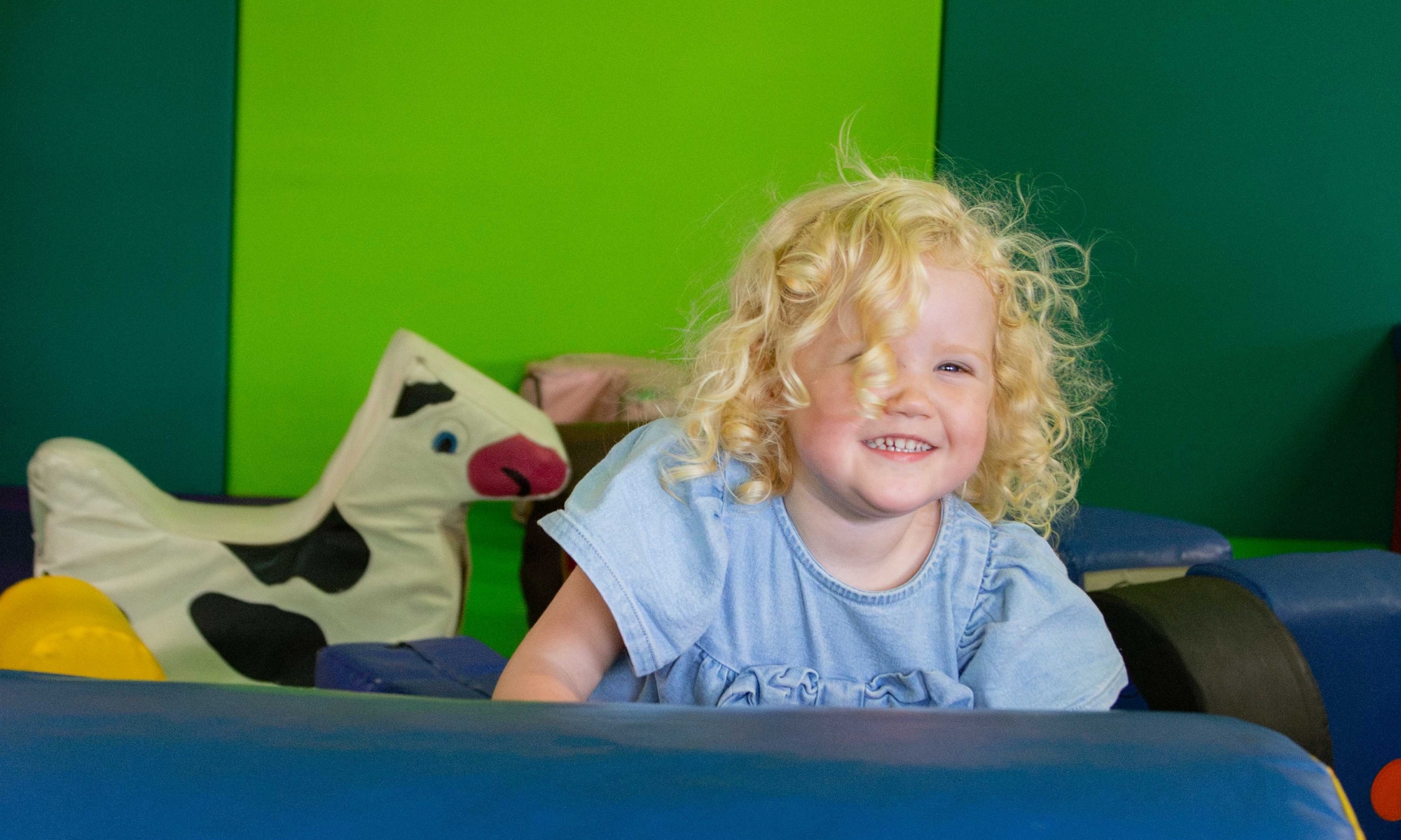 Child smiling while climbing on the soft play at the Play Barn Café at Wroxham Barns.